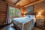 Experience rustic charm in this cozy log cabin bedroom, featuring a comfortable queen-size bed adorned with a nature-inspired comforter.