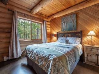 Experience rustic charm in this cozy log cabin bedroom, featuring a comfortable queen-size bed adorned with a nature-inspired comforter.