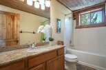 This rustic bathroom features a charming wooden door and ceiling, complemented by a granite countertop and a white vessel sink.