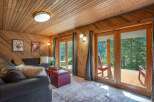 Experience breathtaking mountain views from this cozy living room, featuring warm wood paneling and a comfortable sectional sofa.