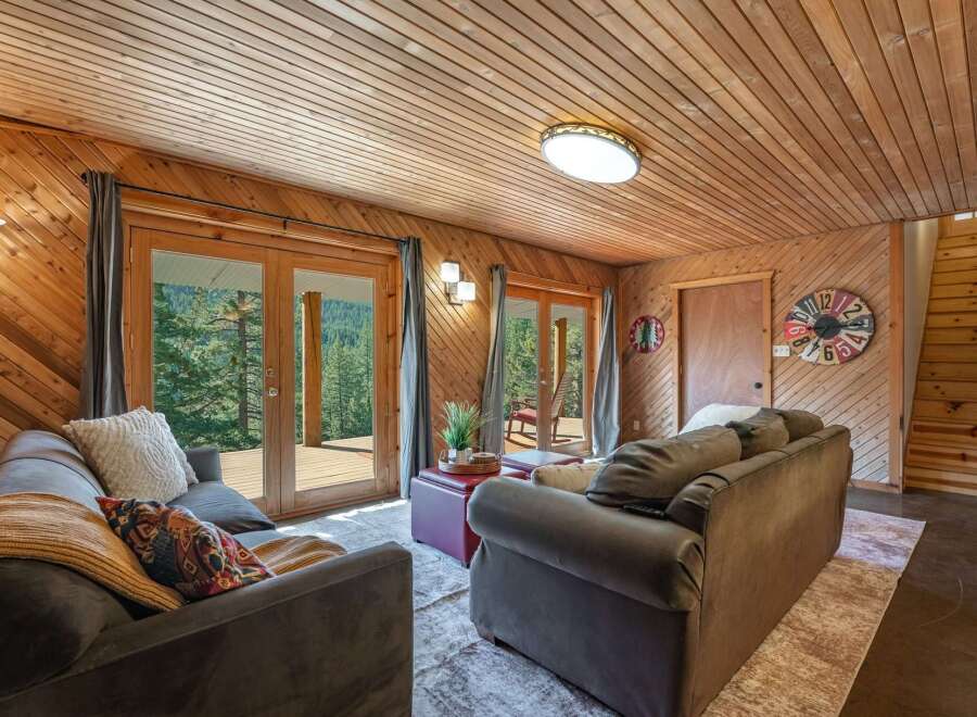 Experience rustic charm in this cozy living room featuring warm wood paneling and a vaulted wood-plank ceiling.