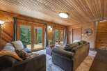 Experience rustic charm in this cozy living room featuring warm wood paneling and a vaulted wood-plank ceiling.