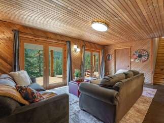 Experience rustic charm in this cozy living room featuring warm wood paneling and a vaulted wood-plank ceiling.