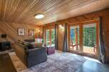Experience rustic charm in this cozy living room, featuring warm wood-paneled walls and a sloped ceiling.