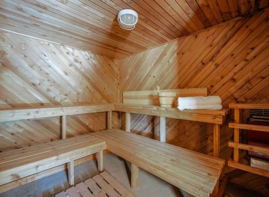 Experience ultimate relaxation in this beautifully crafted wooden sauna, featuring multiple tiered benches for comfortable seating.