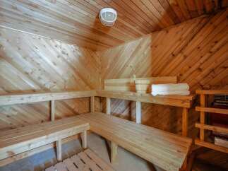Experience ultimate relaxation in this beautifully crafted wooden sauna, featuring multiple tiered benches for comfortable seating.