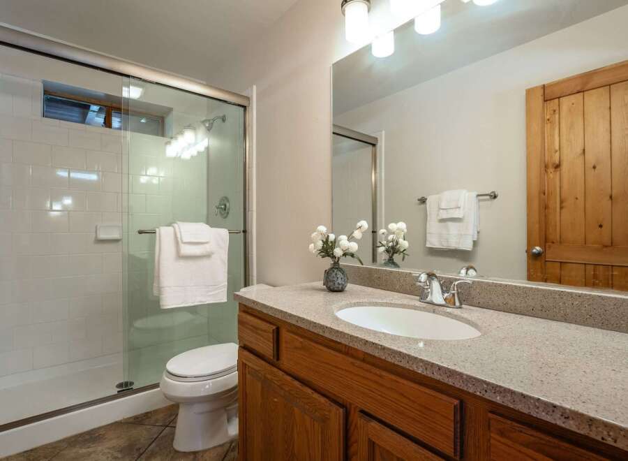 This bright and clean bathroom features a spacious glass-enclosed shower with white subway tile and a convenient toilet.