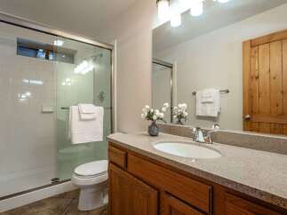 This bright and clean bathroom features a spacious glass-enclosed shower with white subway tile and a convenient toilet.