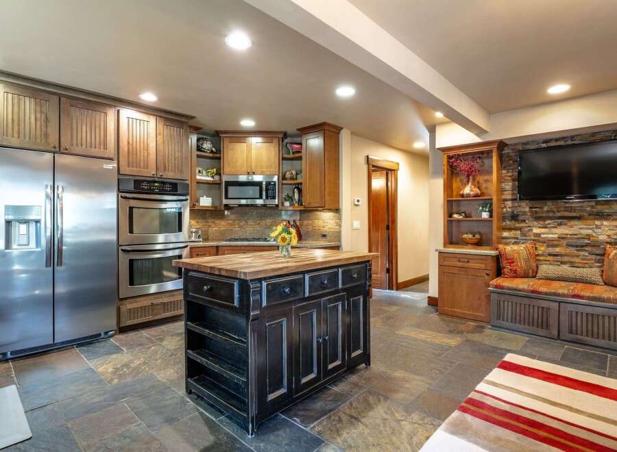 This spacious kitchen boasts a large stainless steel refrigerator, double ovens, and a charming wooden island perfect for meal prep and gathering.