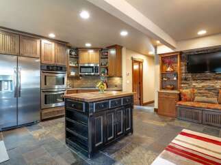 This spacious kitchen boasts a large stainless steel refrigerator, double ovens, and a charming wooden island perfect for meal prep and gathering.