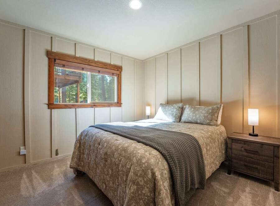 This cozy bedroom features a comfortable queen-sized bed adorned with a patterned comforter and a plush grey throw blanket.