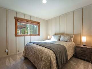 This cozy bedroom features a comfortable queen-sized bed adorned with a patterned comforter and a plush grey throw blanket.