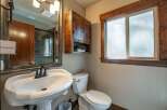 This rustic bathroom features a charming wooden cabinet above a pedestal sink and toilet.