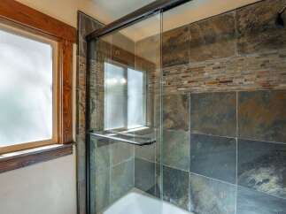 Experience a spa-like retreat in this bathroom featuring a luxurious glass-enclosed shower with striking slate tile accents.
