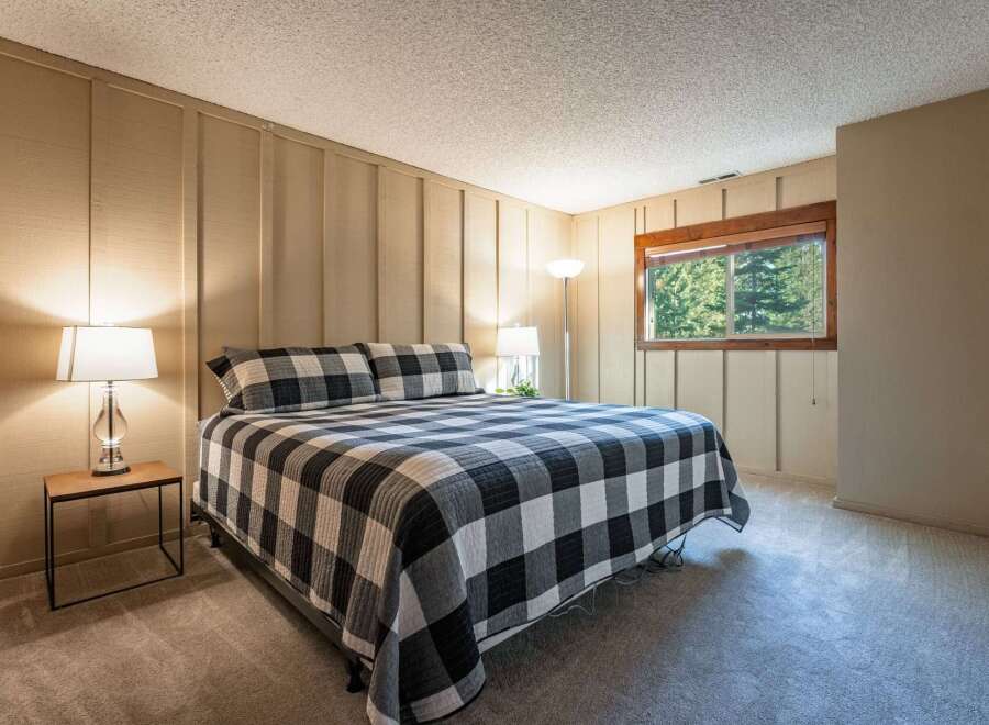Experience cozy comfort in this charming bedroom, featuring a king-sized bed with a classic black and white buffalo check quilt.