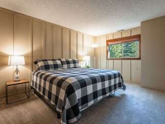 Experience cozy comfort in this charming bedroom, featuring a king-sized bed with a classic black and white buffalo check quilt.