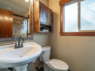 This charming bathroom features a pedestal sink with a vintage-inspired faucet, complemented by a rustic wooden medicine cabinet.