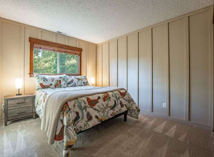 This charming bedroom features a comfortable queen-size bed adorned with a whimsical bird and butterfly print comforter.