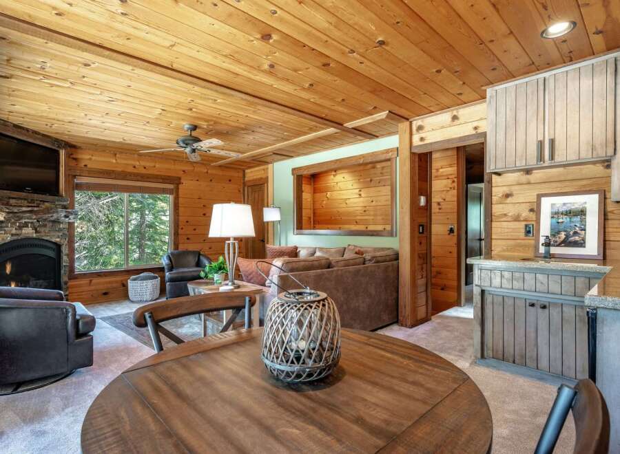 Experience rustic charm in this cozy living space featuring a stone fireplace and a large window with forest views.