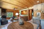 Experience rustic charm in this cozy living space featuring a stone fireplace and a large window with forest views.