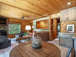 Experience rustic charm in this cozy living space featuring a stone fireplace and a large window with forest views.