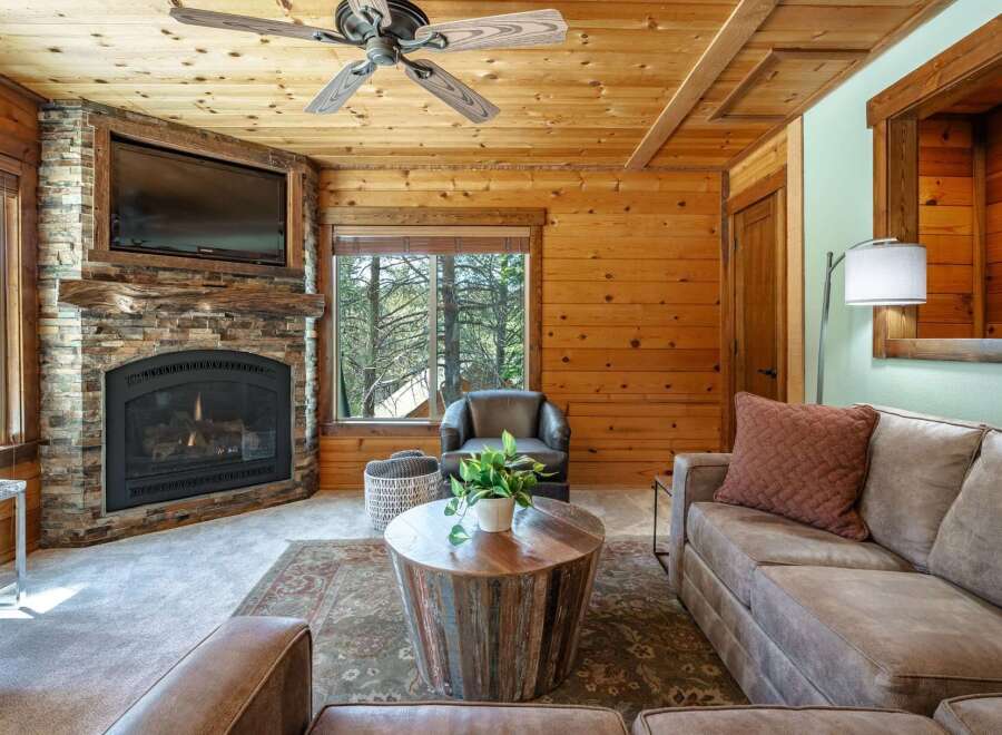 Experience rustic charm in this cozy living room, featuring a stunning stone fireplace and a mounted television perfect for movie nights.