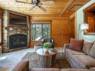 Experience rustic charm in this cozy living room, featuring a stunning stone fireplace and a mounted television perfect for movie nights.
