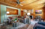 Experience rustic charm in this cozy living area featuring a plush sectional sofa, a unique wooden coffee table, and a convenient wet bar.