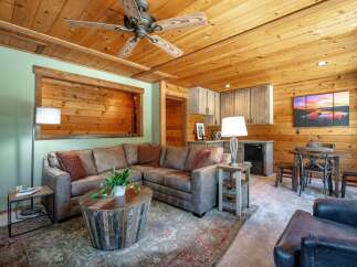 Experience rustic charm in this cozy living area featuring a plush sectional sofa, a unique wooden coffee table, and a convenient wet bar.
