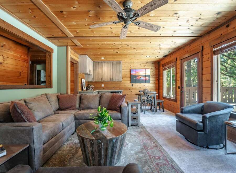 Experience rustic charm in this inviting living space, featuring warm wood paneling throughout and a cozy sectional sofa perfect for relaxation.