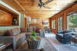 Experience rustic charm in this inviting living space, featuring warm wood paneling throughout and a cozy sectional sofa perfect for relaxation.