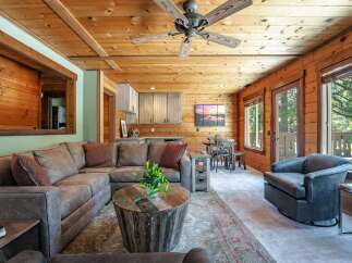 Experience rustic charm in this inviting living space, featuring warm wood paneling throughout and a cozy sectional sofa perfect for relaxation.
