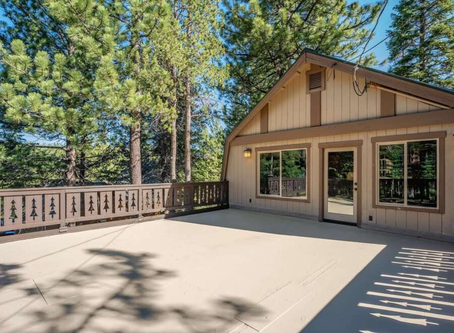 Enjoy the serene mountain lifestyle with this spacious deck, perfect for outdoor entertaining or simply relaxing amidst the towering pine trees.