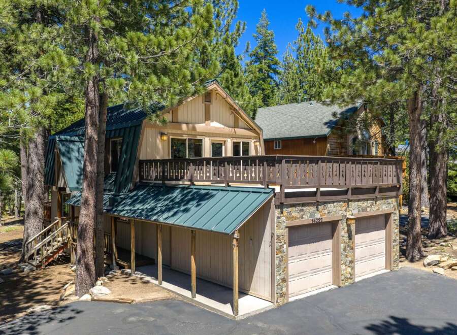 Nestled among tall pine trees, this charming mountain home offers a unique A-frame design with a durable metal roof.