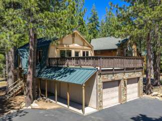 Nestled among tall pine trees, this charming mountain home offers a unique A-frame design with a durable metal roof.