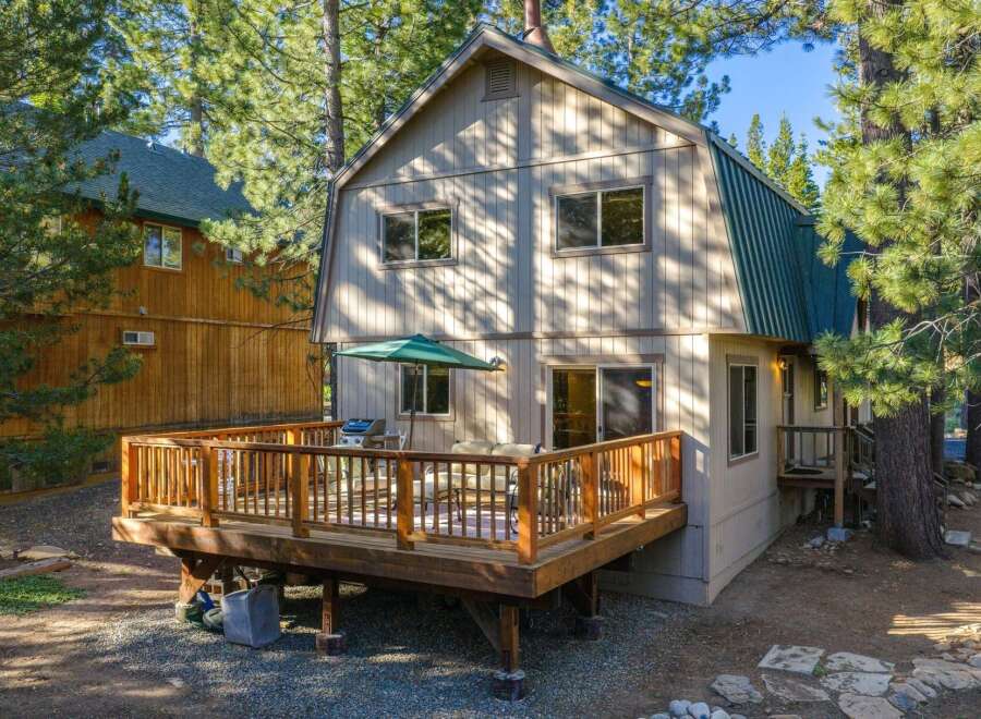 Enjoy outdoor living on this spacious wooden deck, complete with a barbecue grill and comfortable seating, perfect for entertaining guests.