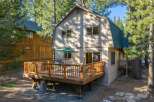 Enjoy outdoor living on this spacious wooden deck, complete with a barbecue grill and comfortable seating, perfect for entertaining guests.