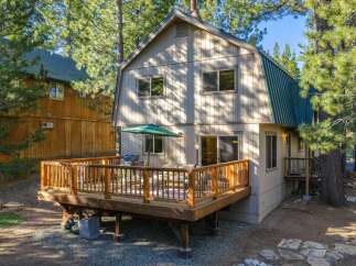 Enjoy outdoor living on this spacious wooden deck, complete with a barbecue grill and comfortable seating, perfect for entertaining guests.
