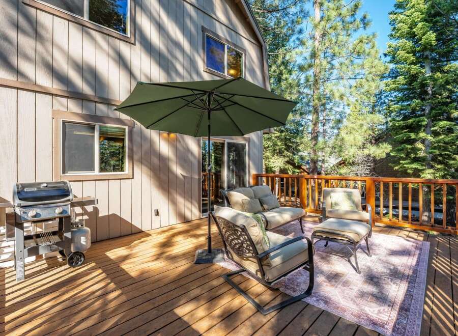 Enjoy outdoor living on this spacious wooden deck, perfect for entertaining or relaxing amidst the tall pine trees.