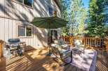 Enjoy outdoor living on this spacious wooden deck, perfect for entertaining or relaxing amidst the tall pine trees.