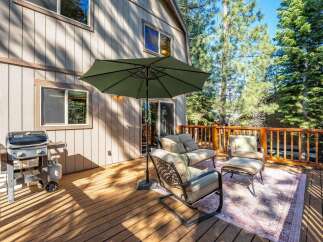 Enjoy outdoor living on this spacious wooden deck, perfect for entertaining or relaxing amidst the tall pine trees.