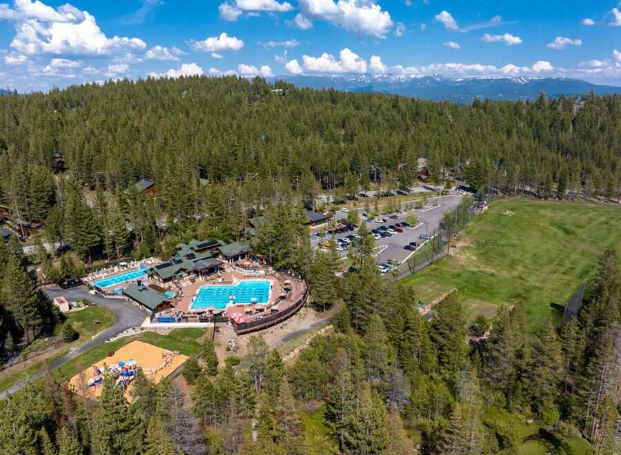 Discover this stunning mountain resort featuring multiple swimming pools, a playground, and a golf course, all nestled within a dense pine forest.