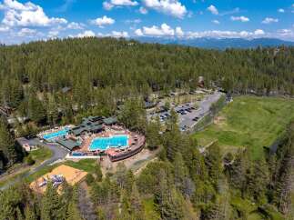 Discover this stunning mountain resort featuring multiple swimming pools, a playground, and a golf course, all nestled within a dense pine forest.
