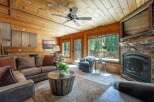 Experience rustic charm in this cozy living room featuring a stunning stone fireplace and a warm, wood-paneled ceiling.
