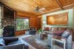 Experience rustic charm in this cozy living room, featuring a striking stone fireplace and a mounted television.