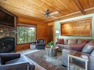 Experience rustic charm in this cozy living room, featuring a striking stone fireplace and a mounted television.