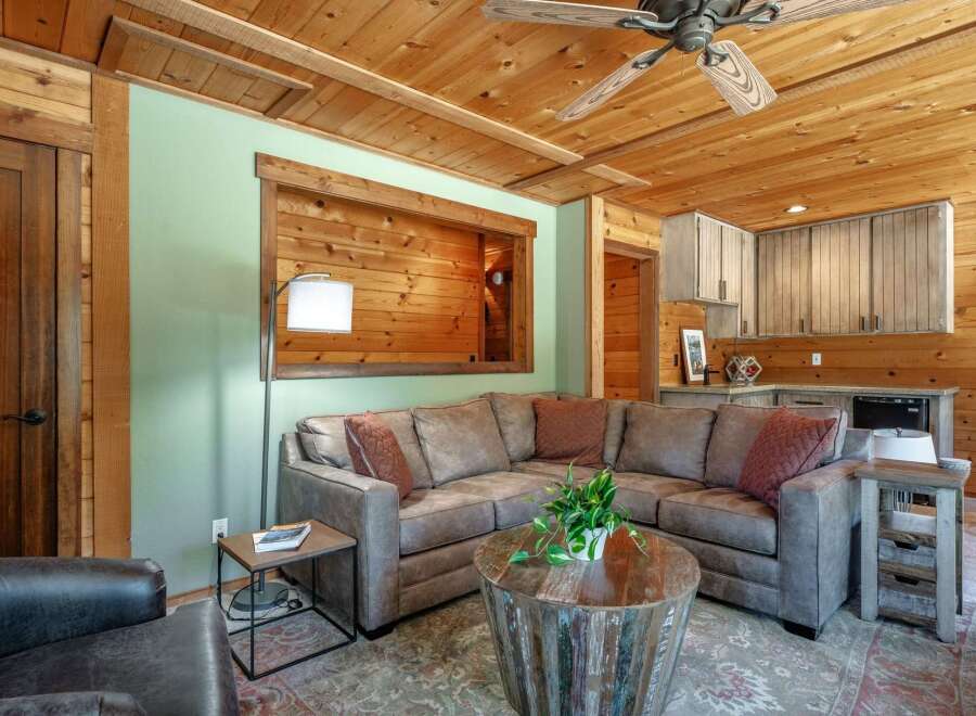 Experience rustic charm in this inviting living space, featuring a comfortable sectional sofa centered around a unique distressed wood coffee table.