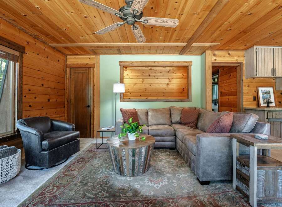 Experience rustic charm in this cozy living room, featuring warm wood paneling throughout and a striking wood-slat accent wall.
