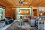 Experience rustic charm in this cozy living room, featuring warm wood paneling throughout and a striking wood-slat accent wall.