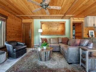 Experience rustic charm in this cozy living room, featuring warm wood paneling throughout and a striking wood-slat accent wall.